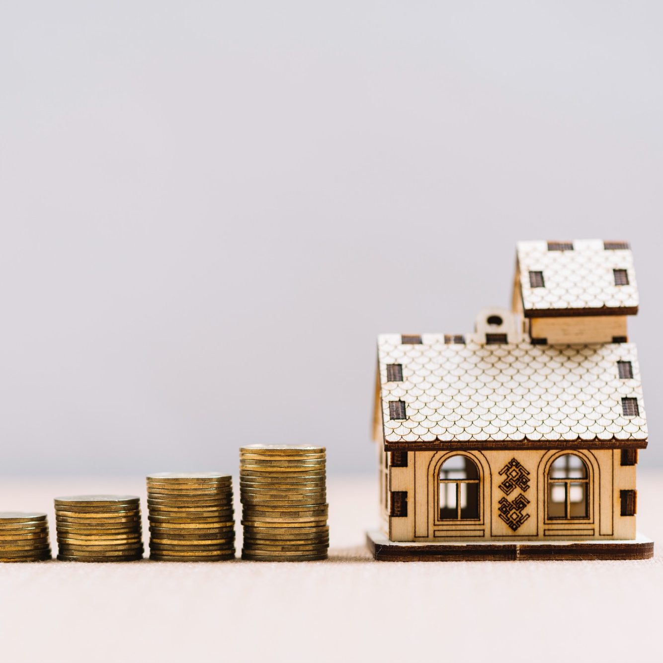 Investissement locatif rentable : maison miniature en bois et piles de pièces, accompagnement Loany
