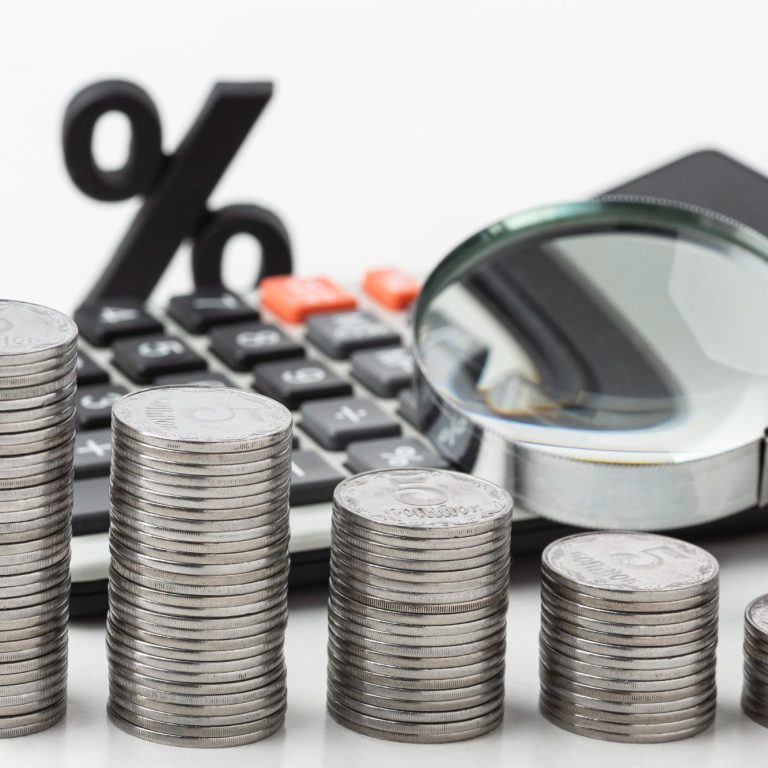 Service de courtage Loany par Jérôme Guilloux : piles de pièces, calculatrice, loupe et taux d’intérêt