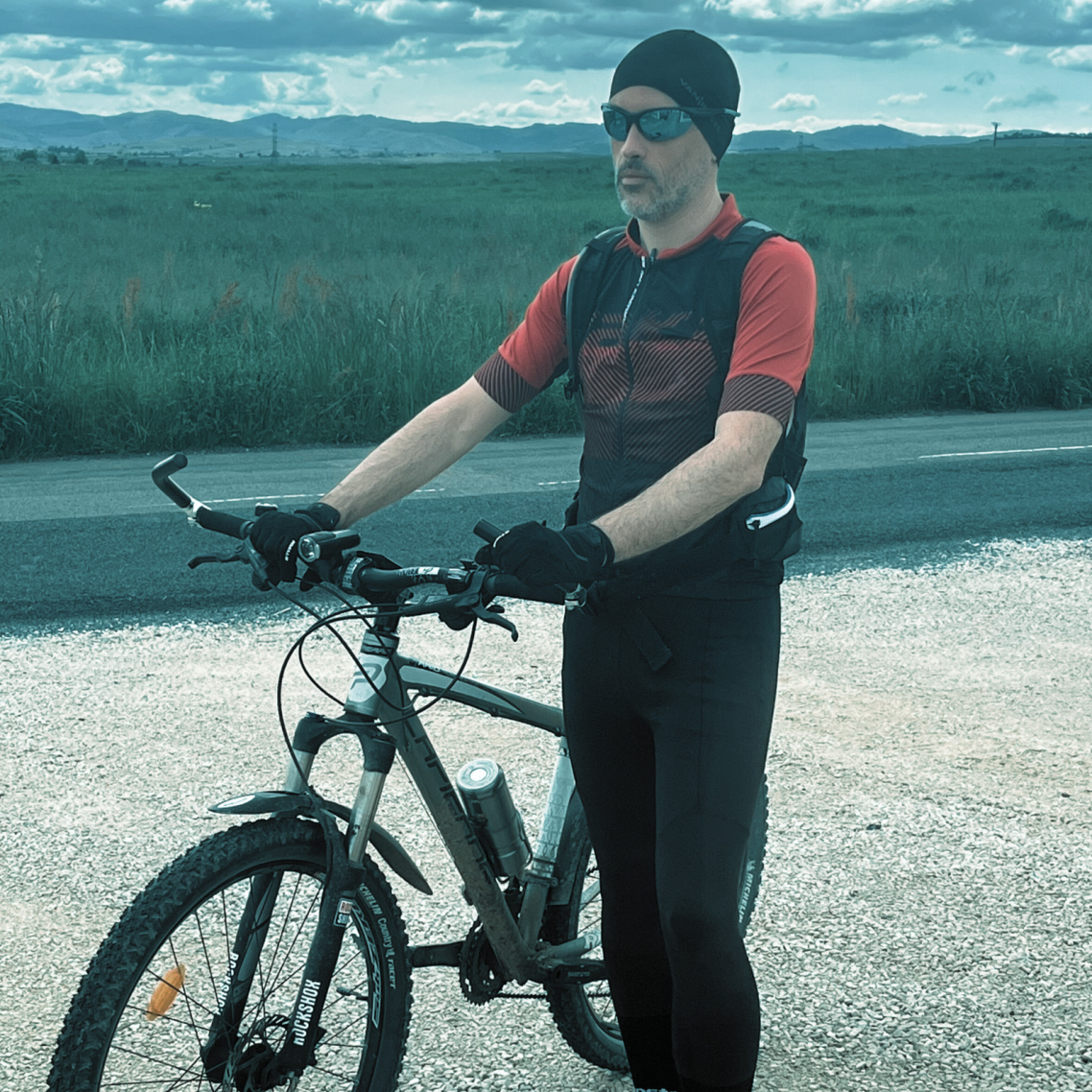 Jérôme Guilloux, passionné de sport, debout avec son VTT, paysage nordique – Qui suis-je Loany
