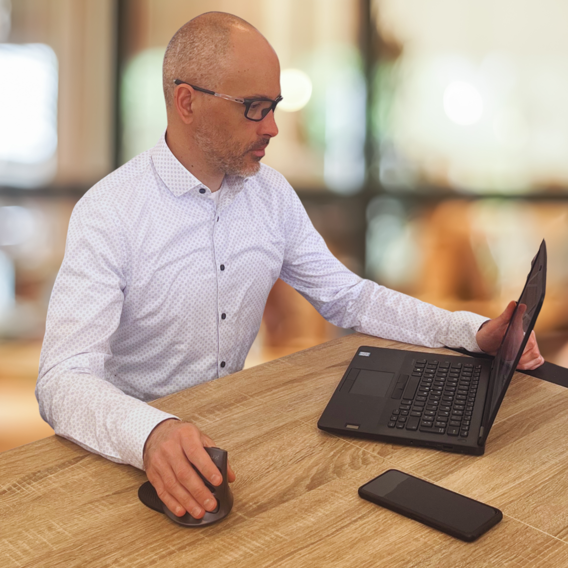 Jérôme Guilloux travaillant sur ordinateur portable, chemise blanche, posture concentrée – Qui suis-je Loany